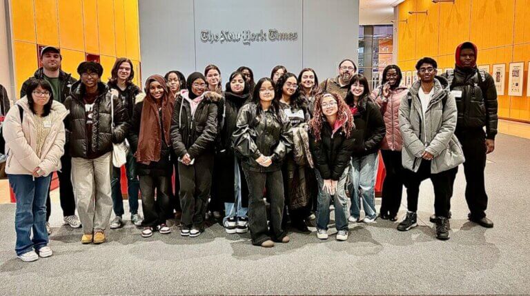 Group of students and adults pose for photo on a visit to The New York Times office