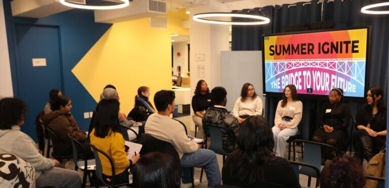 Alumni panelists are seated at the front with screen showing "Summer Ignite: The Bridge to Your Future" with students seated in front of them