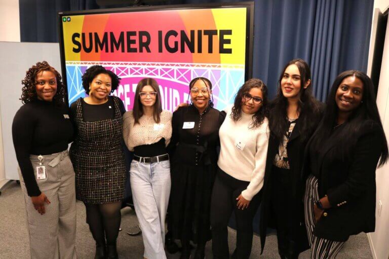 College Persistence team with alumni panelists stand in front of screen with event name Summer Ignite
