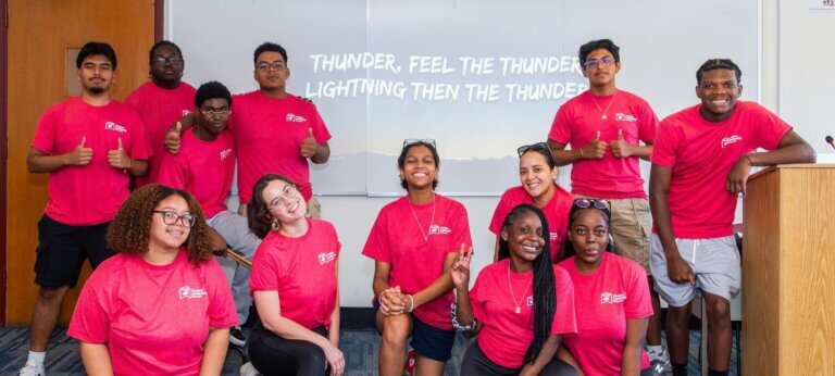High school students and college counselors wear matching red t-shirts and pose for photo during college readiness retreat