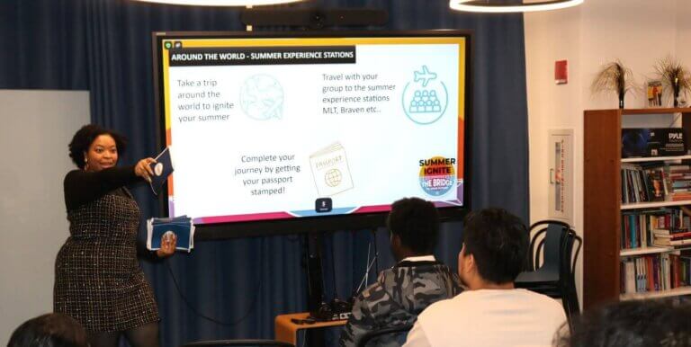 Staff member at front of room points to student, with flyers in her hand