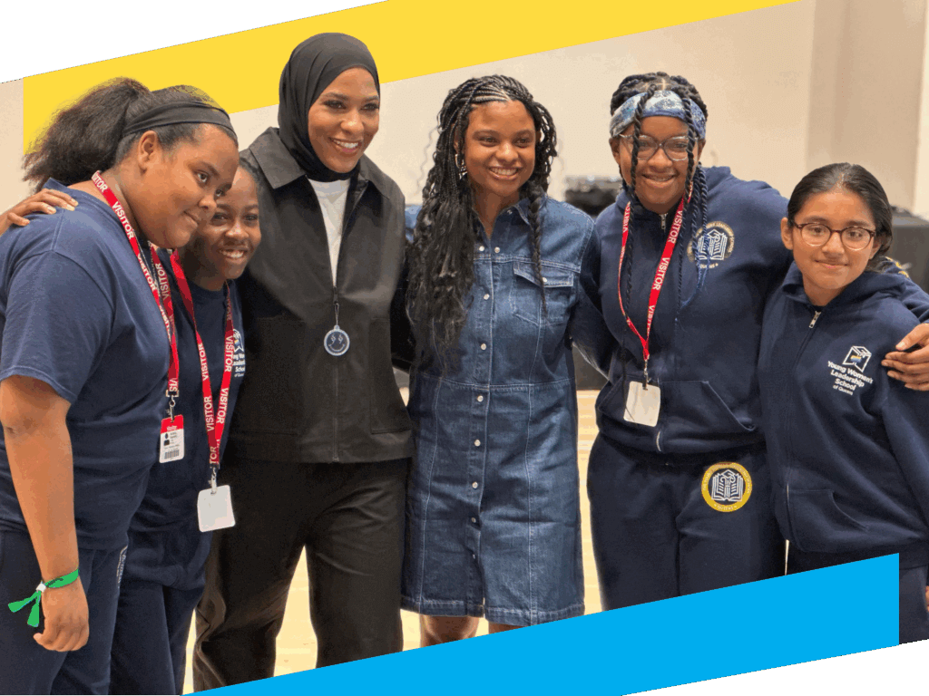 Five girls and one woman stand together indoors, smiling at the camera.