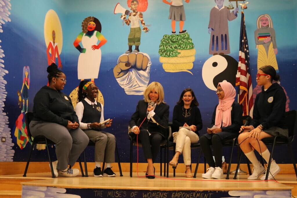 students seated on stage with Brigitte Macron, a former teacher and wife of French President Emmanuel Macron