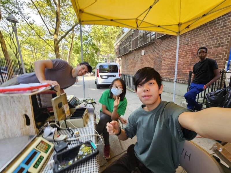 Four young people set up a farmers market stand outdoors