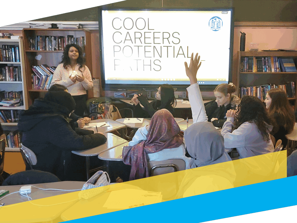 A "Cool Careers, Potential Paths" volunteer stands at the front of a classroom leading a discussion; students sit at tables, one with a hand raised, and a screen displays “Cool Careers Potential Paths”.