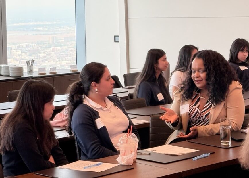 An adult and two students speak with each other in a conference room