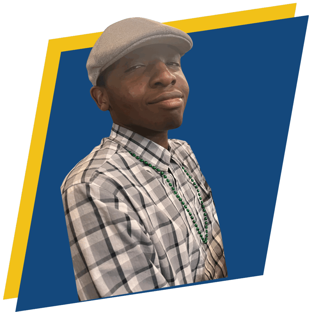 A person wearing a gray flat cap, plaid shirt, and green bead necklace stands in front of a blue background with a yellow border.
