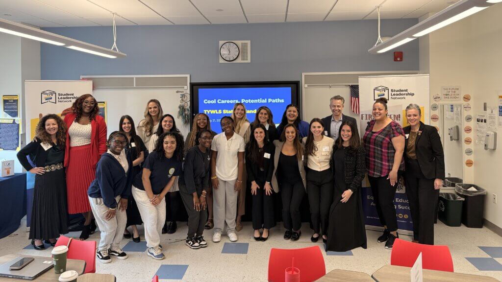 A diverse group of professionals and students pose together in a classroom, standing in front of a presentation screen titled Cool Careers, Potential Paths.
