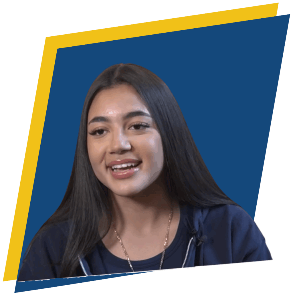 A young woman with long dark hair is smiling, wearing a dark top and a necklace, set against a blue background with a yellow border.