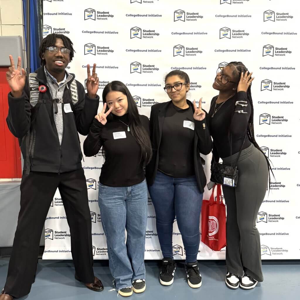 Students smiling stand in front of a CollegeBound Initiative step-and-repeat banner