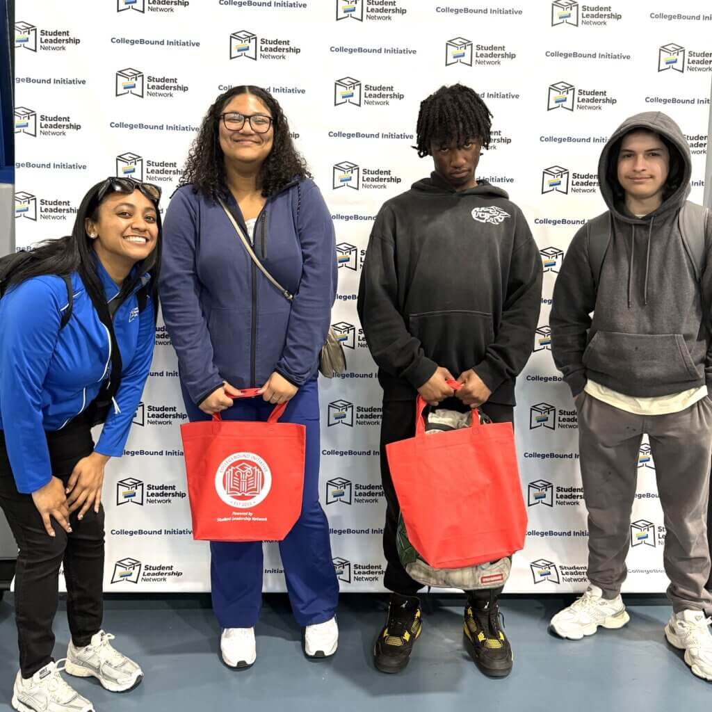 Students smiling stand in front of a CollegeBound Initiative step-and-repeat banner