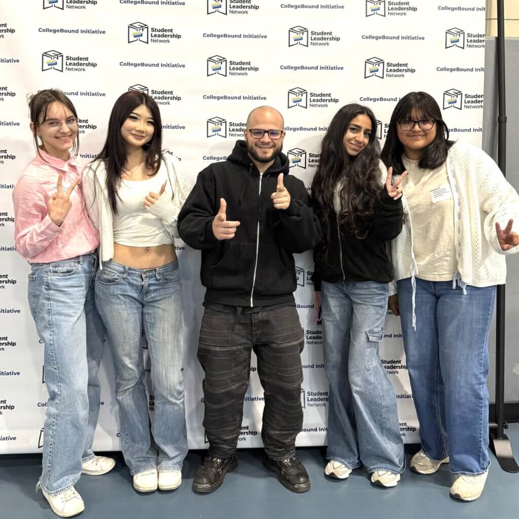 Students smiling stand in front of a CollegeBound Initiative step-and-repeat banner
