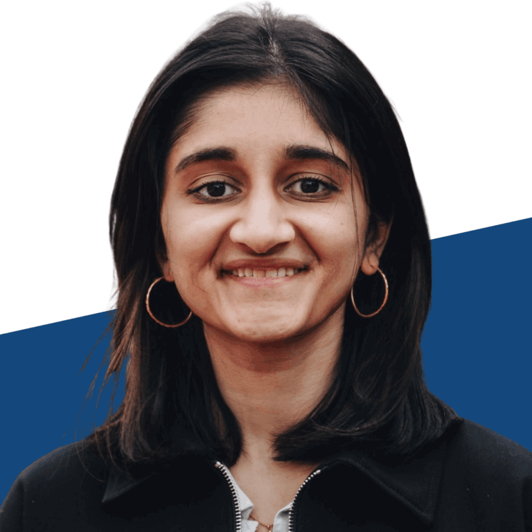 A woman with straight dark hair, wearing hoop earrings and a black jacket, smiles in front of a white and blue background.