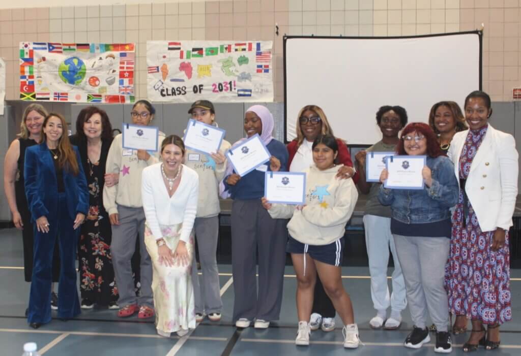 A group of people pose indoors, with several students holding certificates in front.